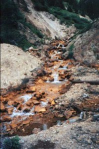 When pyrite mixes with air and water to produce sulfuric acid, iron is left to settle out giving areas where this happens an orange rust color – a tell-tale sign of acid mine drainage.